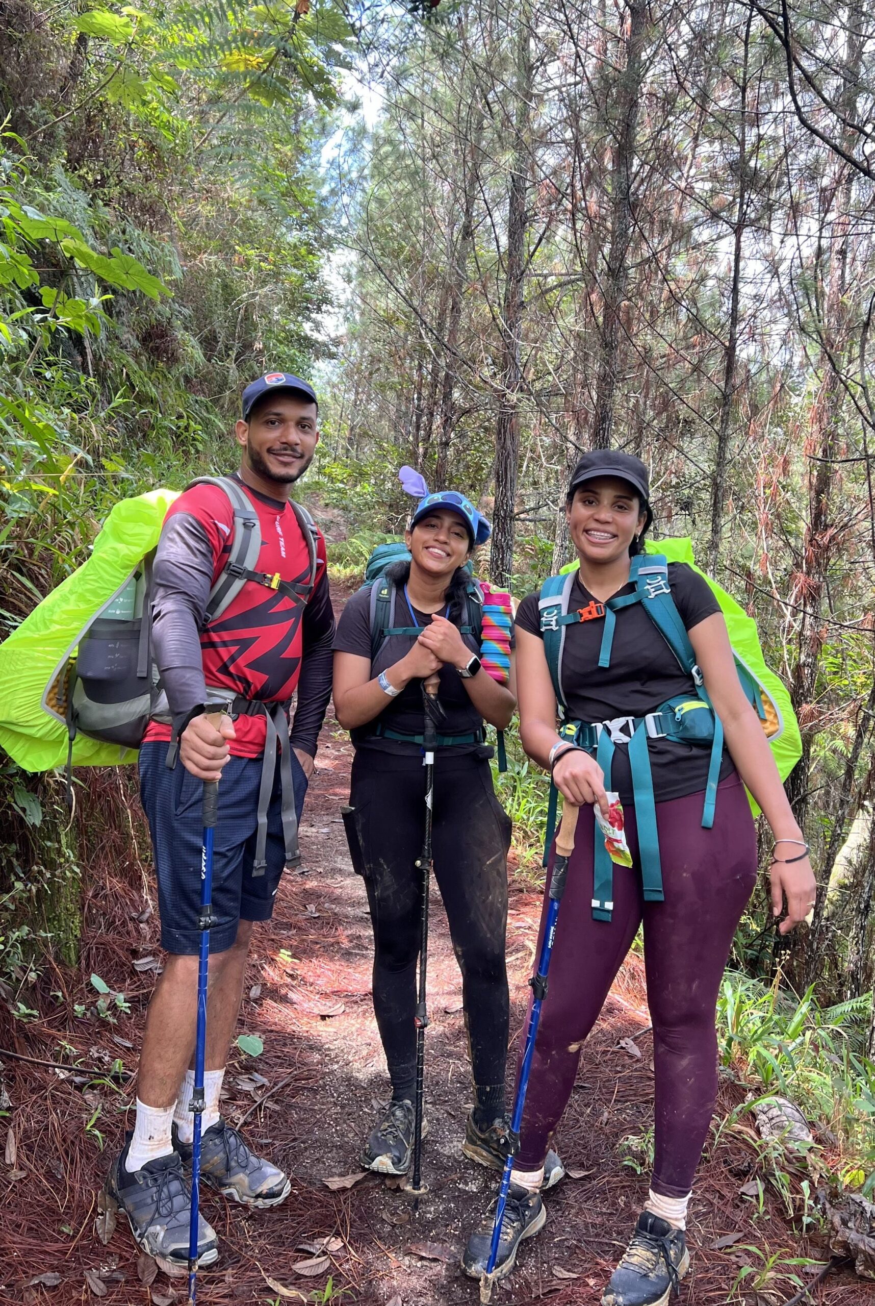 Tres personas con mochilas de senderismo posando en un sendero forestal